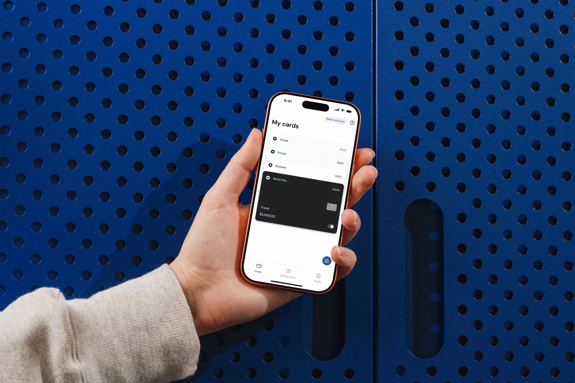 Clara app in a hand against a blue perforated wall